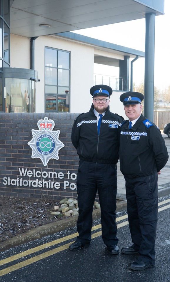 Picture of PCSO Matthew Stepney and PCSO Colin Stepney standing next to the force crest at HQ